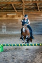 Pretty young girl doing equestrian show jumping on her pony in a farm Royalty Free Stock Photo