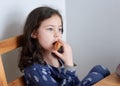 pretty young girl eating bread and butter in her pajamas at breakfast