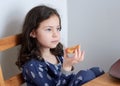 pretty young girl eating bread and butter in her pajamas at breakfast