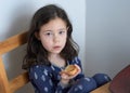 pretty young girl eating bread and butter in her pajamas at breakfast