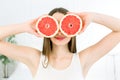 Pretty young girl with grapefruit slices in front of her eyes. Beautiful woman holding grapefruit slice hiding eyes Royalty Free Stock Photo