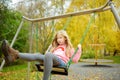 Pretty young girl having fun on a playground in beautiful autumn park. Cute preteen child playing outdoors in late autumn. Outdoor