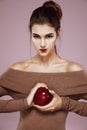 Pretty young girl holding red apple in hands looking at camera brutally. Royalty Free Stock Photo