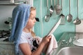 Pretty young girl inspecting dishes while drying up at the kitchen sink