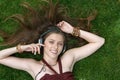 Pretty young girl listen music in headphones lying on grass Royalty Free Stock Photo