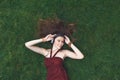 Pretty young girl listening music in earphones lying on grass Royalty Free Stock Photo