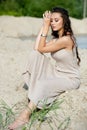 Pretty young girl model with long dark hair sitting on the sand. Desert background Royalty Free Stock Photo