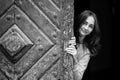 Pretty young girl peering from behind ancient wooden door Royalty Free Stock Photo