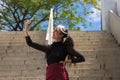 Pretty young girl in punk style taking photos with her mobile phone on a staircase in the park. Technology and beauty concept Royalty Free Stock Photo