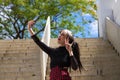 Pretty young girl in punk style taking photos with her mobile phone on a staircase in the park. Technology and beauty concept Royalty Free Stock Photo