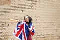 Pretty young girl in punk style threatening with a baseball bat. She carries the London flag on her shoulders