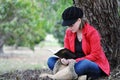 Pretty young girl reading holy bible under big tree in park Royalty Free Stock Photo