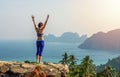 Pretty young girl is refreshing by raising arms on rock at viewpoint of Ko Phi Phi Don Island. Scenery of Ko Phi Phi Islands in