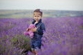 Pretty young girl sitting in lavender field in nice hat boater with purple flower on it. Royalty Free Stock Photo