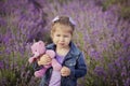 Pretty young girl sitting in lavender field in nice hat boater with purple flower on it. Royalty Free Stock Photo