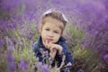 Pretty young girl sitting in lavender field in nice hat boater with purple flower on it. Royalty Free Stock Photo