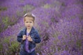 Pretty young girl sitting in lavender field in nice hat boater with purple flower on it. Royalty Free Stock Photo