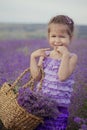 Pretty young girl sitting in lavender field in nice hat boater with purple flower on it. Royalty Free Stock Photo