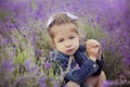 Pretty young girl sitting in lavender field in nice hat boater with purple flower on it. Royalty Free Stock Photo