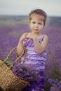 Pretty young girl sitting in lavender field in nice hat boater with purple flower on it. Royalty Free Stock Photo