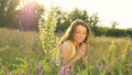 Pretty young girl is sitting in the middle of the field with flowers during summer time and sneezing, hypersensitivity