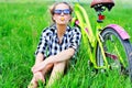 Pretty young girl sitting next to bike in grass