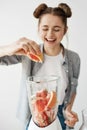 Pretty young girl smiling blending detox refreshing grapefruit smoothie over white wall. Healthy food concept.