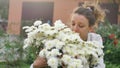 Pretty young girl is standing near a bush of white chrysanthemums in park during spring time, hypersensitivity, asthma