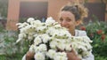 Pretty young girl is standing near a bush of white chrysanthemums in park during spring time, hypersensitivity, asthma