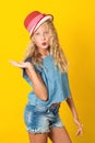 Pretty young girl in summer hat over yellow background. Cute girl sending kiss. Summer fashion. Happy girl, denim style