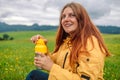 Happy traveler young woman resting in the mountains and drinking tea from thermos at sunset in spring or summer season. Royalty Free Stock Photo