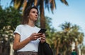 Pretty young girl walks through the Park after office work and chats in messengers with colleagues manager using Internet device