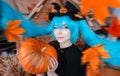 Pretty young girl witch halloween costume dressed in black with pumpkins