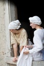 Pretty young girls at the window in medieval costume, looking down and smiling