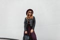 Pretty young hipster woman in stylish sunglasses in a trendy leather jacket in cape pants with a fashionable backpack Royalty Free Stock Photo