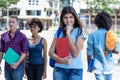 Pretty young hispanic female student with group of young adults