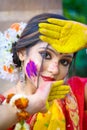 Pretty young indian girl showing colourful palm and celebrating Holi with colour splash, popular hindu festival celebrated across Royalty Free Stock Photo