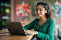 Pretty indian woman studying online at cafe, using laptop, empty space Royalty Free Stock Photo