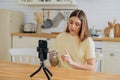 Lady with shiny bionic prosthesis shooting video in kitchen