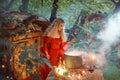 Pretty young lady with blond curly hair above big magic cauldron with smoke and bottles with liquids, forest nymph in