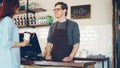 Pretty young lady is buying takeaway coffe in coffee-shop and paying with smartphone making contactless payment. Modern Royalty Free Stock Photo