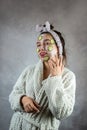 pretty young lady with facial mask in cream and cucumber cosmetics procedure