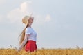 Pretty young lady in a hat stands in a wheat field and looking at the sky. Side view Royalty Free Stock Photo