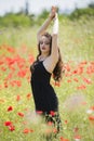 Pretty young lady sitting among poppies field Royalty Free Stock Photo