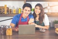 Pretty young lady using laptop with her boyfriend. Asian couple doing online shopping together on weekend.