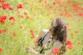 Pretty young lady sitting among poppies field Royalty Free Stock Photo