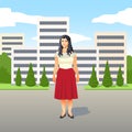 Pretty young Latino woman in a stylish red skirt standing smiling in the street Royalty Free Stock Photo