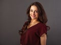 Pretty young makeup toothy enjoying smiling woman with long brown healthy curly healthy brown hair style in red shirt clothing. Royalty Free Stock Photo