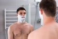 Pretty young man with shaving foam on his cheeks Royalty Free Stock Photo