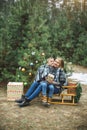 Pretty young mother with child son while sitting on the wooden decorated sledge outdoors in winter forest, covered with Royalty Free Stock Photo